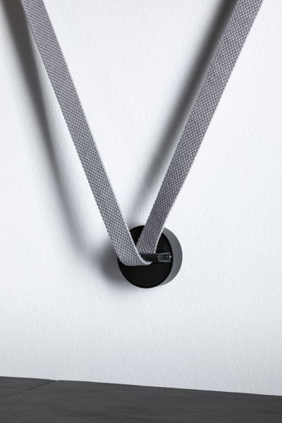 Crochet mural noir en métal avec sangle en tissu gris sur mur blanc pour décoration moderne