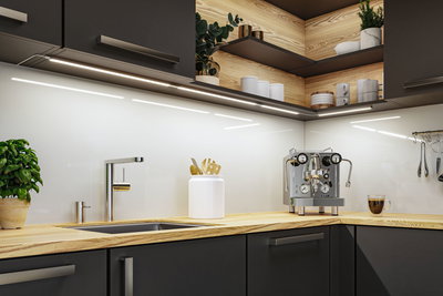 Moderne køkken med træbordplade, rustfri stålvaskarmatur og LED-underkabinetbelysning til lys arbejdsplads.