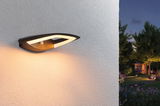 Modern black LED outdoor wall light with warm white illumination and motion sensor on white wall.