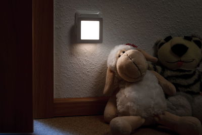 Weißes LED-Nachtlicht aus Kunststoff an Wand neben Kuscheltieren für sanfte Beleuchtung im Kinderzimmer
