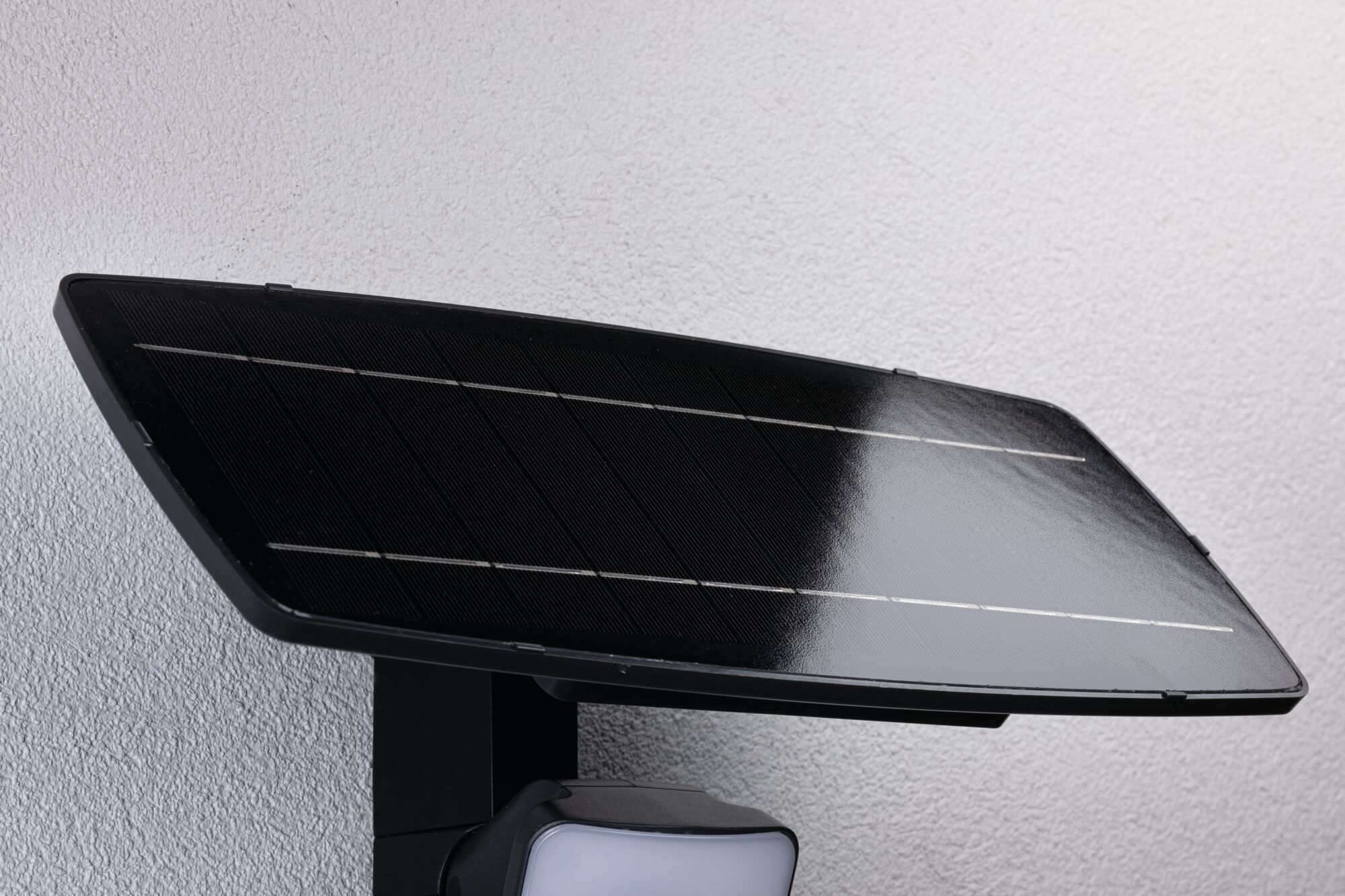 Panneau solaire en verre noir avec lampe LED fixé sur mur blanc pour éclairage extérieur économe en énergie