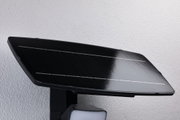 Panneau solaire en verre noir avec lampe LED fixé sur mur blanc pour éclairage extérieur économe en énergie