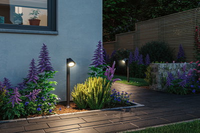 Schwarze Außenwandleuchten beleuchten Gartenweg mit lila und gelben Blumen in moderner Landschaftsgestaltung.