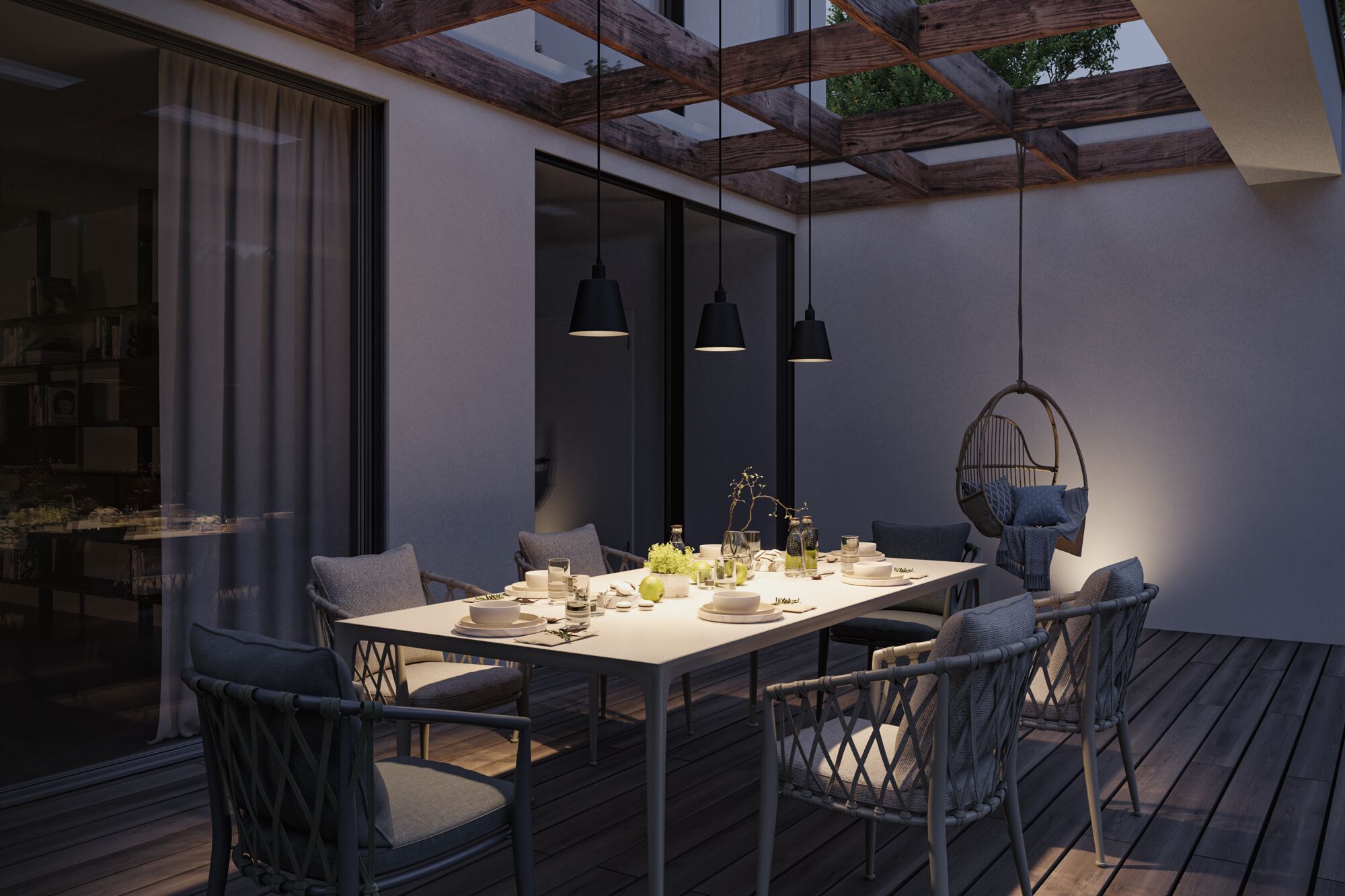 Modern outdoor dining area with white table, grey chairs, and black pendant lights creating cozy atmosphere