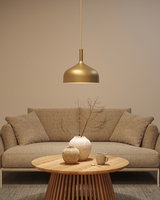 Goldfarbene Metall-Hängeleuchte über rundem Holztisch mit Keramikvasen und beigem Sofa im Wohnzimmer