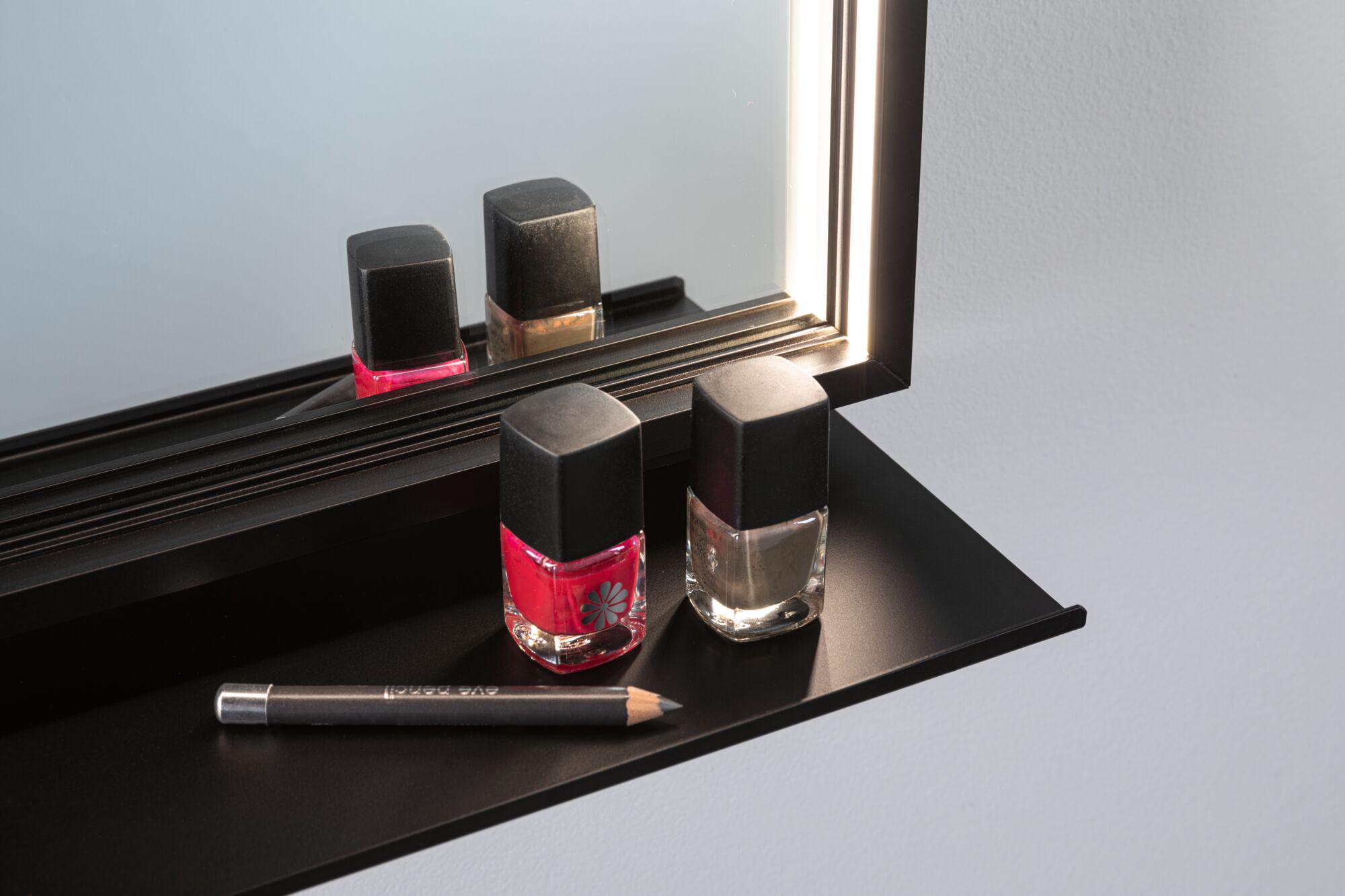 Black wall shelf with mirror and LED light, featuring red and grey nail polish bottles and a black pencil.