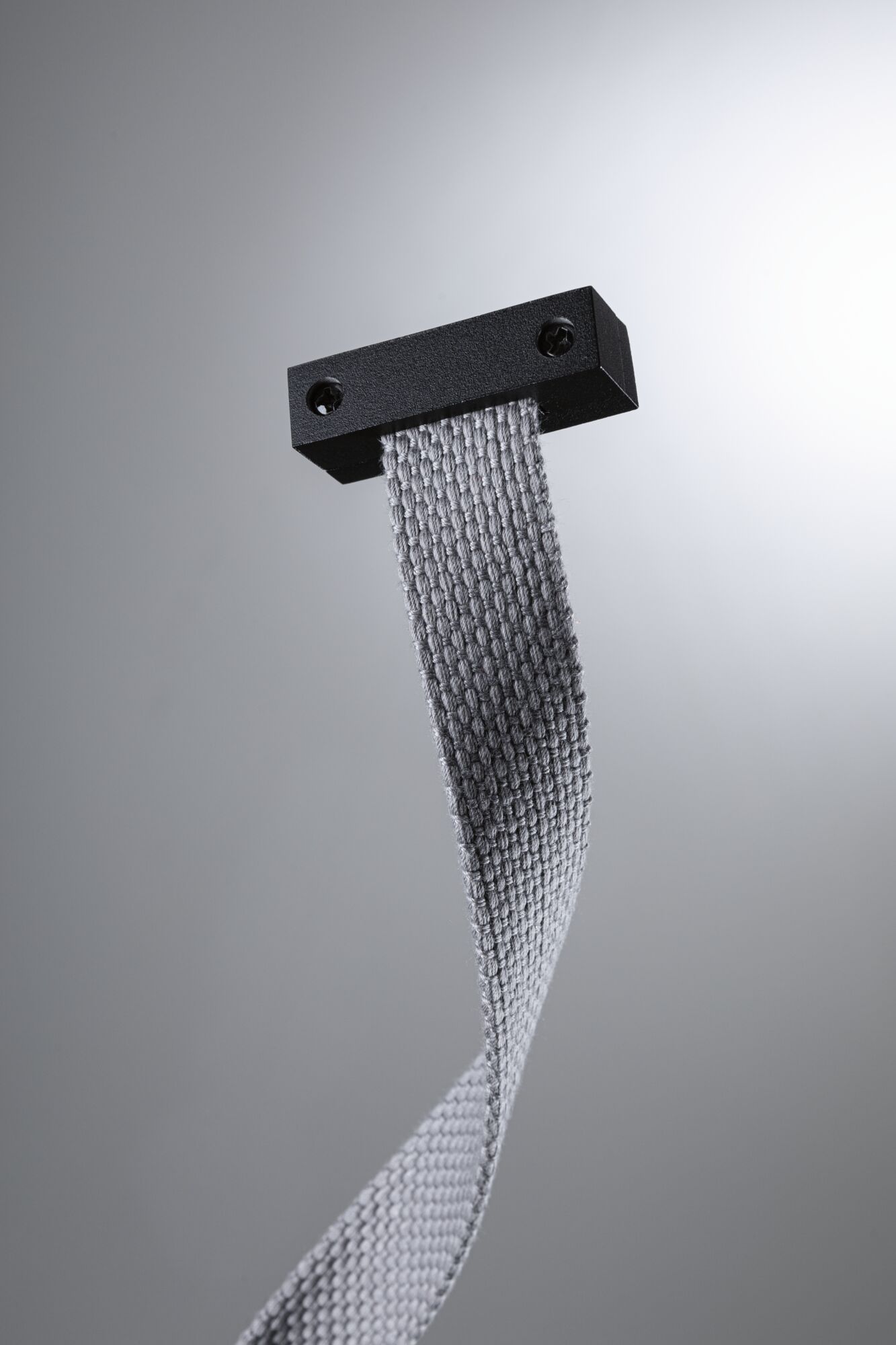 Gråt tekstilbånd med sort metalholder til fleksibel montering, moderne design.