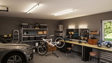 Moderne Werkstatt mit LED-Deckenleuchten und Arbeitsbeleuchtung über Werkbank in Grau und Holz.