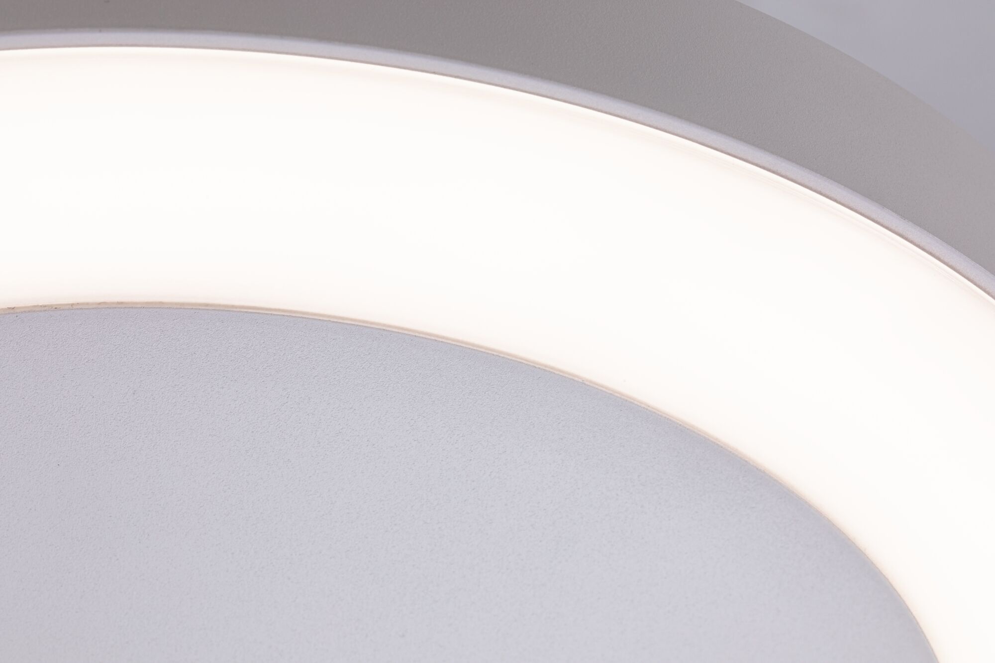 Close-up of round ceiling light with white plastic diffuser and grey frame, LED lighting fixture