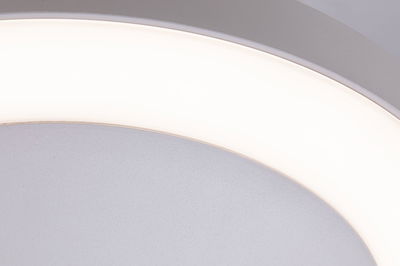 Close-up of round ceiling light with white plastic diffuser and grey frame, LED lighting fixture