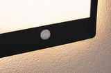 Black LED wall light with integrated white motion sensor mounted on textured wall lighting