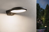 Schwarze LED-Außenwandleuchte aus Metall mit Bewegungsmelder an weißer Wand im Garten.