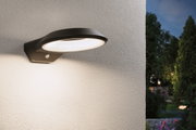 Schwarze LED-Außenwandleuchte aus Metall mit Bewegungsmelder an weißer Wand im Garten.