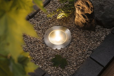 Erdstrahler aus gebürstetem Edelstahl mit warmweißem LED-Licht im Kiesbeet für Gartenbeleuchtung