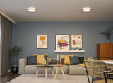 Modernes Wohnzimmer mit grauem Sofa, gelben Kissen, blauen Wänden und zwei runden Deckenleuchten.