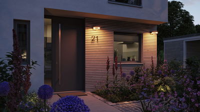 Moderne buitenverlichting met warmwitte LED-ring aan houten gevel naast huisdeur nummer 21 bij schemering