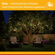 Garten mit solarbetriebenen Lichterketten an Baum und Sitzbereich bei Nacht mit Dämmerungssensor