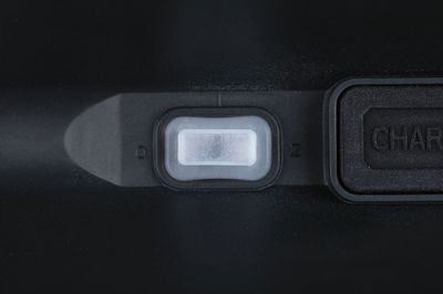 Close-up of white plastic switch on black casing with charging port next to it
