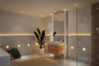 Moderne badkamer met grijze tegels, houten wastafelmeubel en warmwit LED-accentverlichting