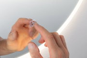 Hand berührt transparenten Touch-Schalter mit Ein-Aus-Symbol vor rundem LED-Spiegel mit weißem Licht