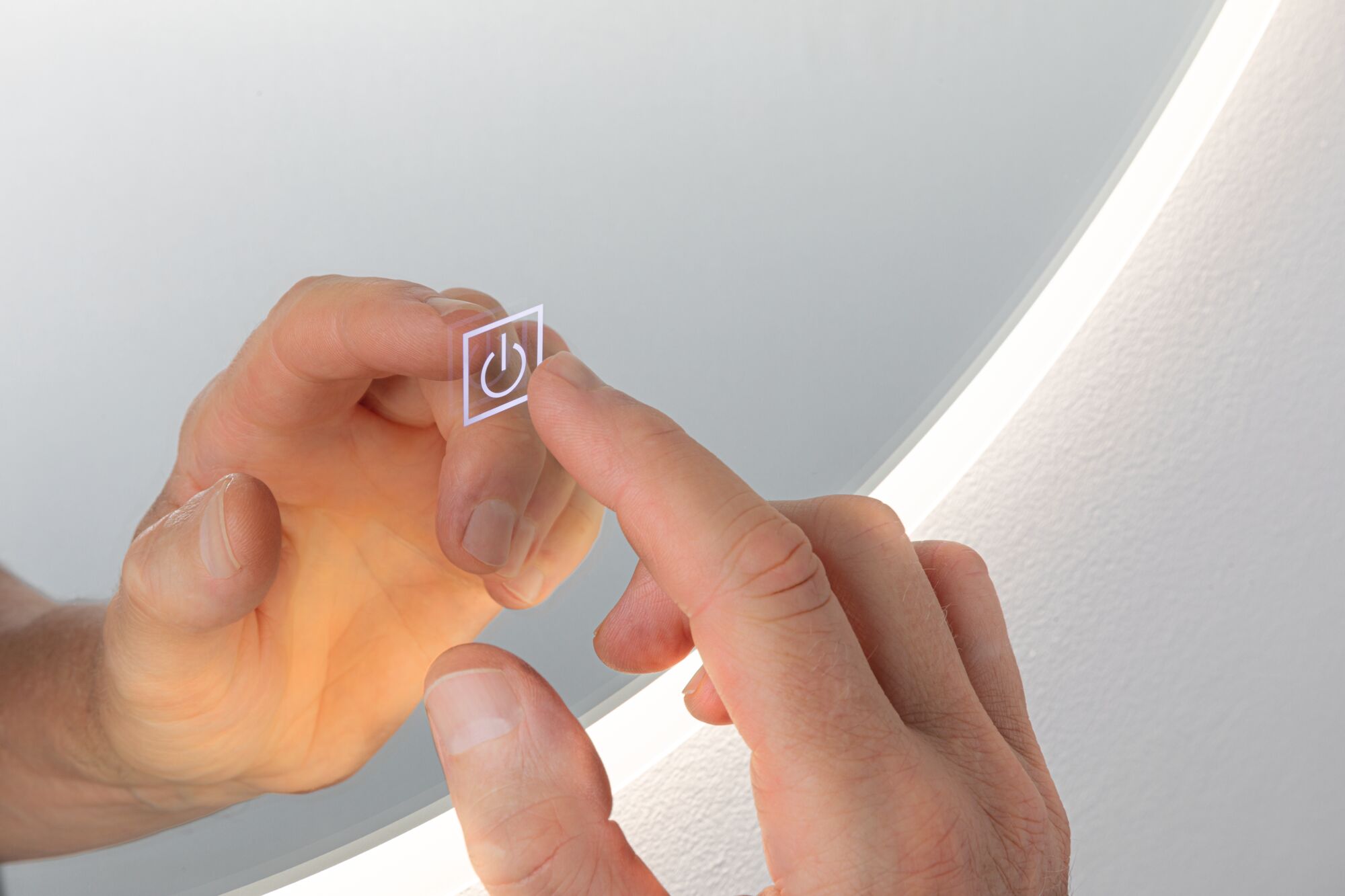Hand berührt transparenten Touch-Schalter mit Ein-Aus-Symbol vor rundem LED-Spiegel mit weißem Licht