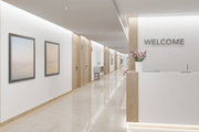 Moderner Empfangsbereich mit weißem Tresen, Holzdetails und LED-Deckenbeleuchtung im Flur.