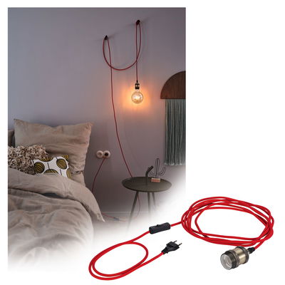Red textile cable with switch and bulb socket, stylishly mounted on bedroom wall for lighting.