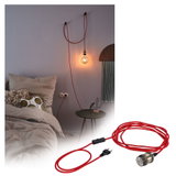 Red textile cable with switch and bulb socket, stylishly mounted on bedroom wall for lighting.