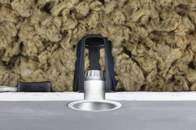 Silver recessed LED spotlight with black bracket and insulation in ceiling cavity for energy-efficient lighting