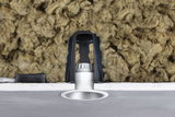 Silver recessed LED spotlight with black bracket and insulation in ceiling cavity for energy-efficient lighting