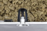 Silver recessed LED spotlight with black bracket and insulation in ceiling cavity for energy-efficient lighting