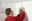 Homme en pull rouge mesure un mur blanc avec une règle et un crayon pour installation d'éclairage.
