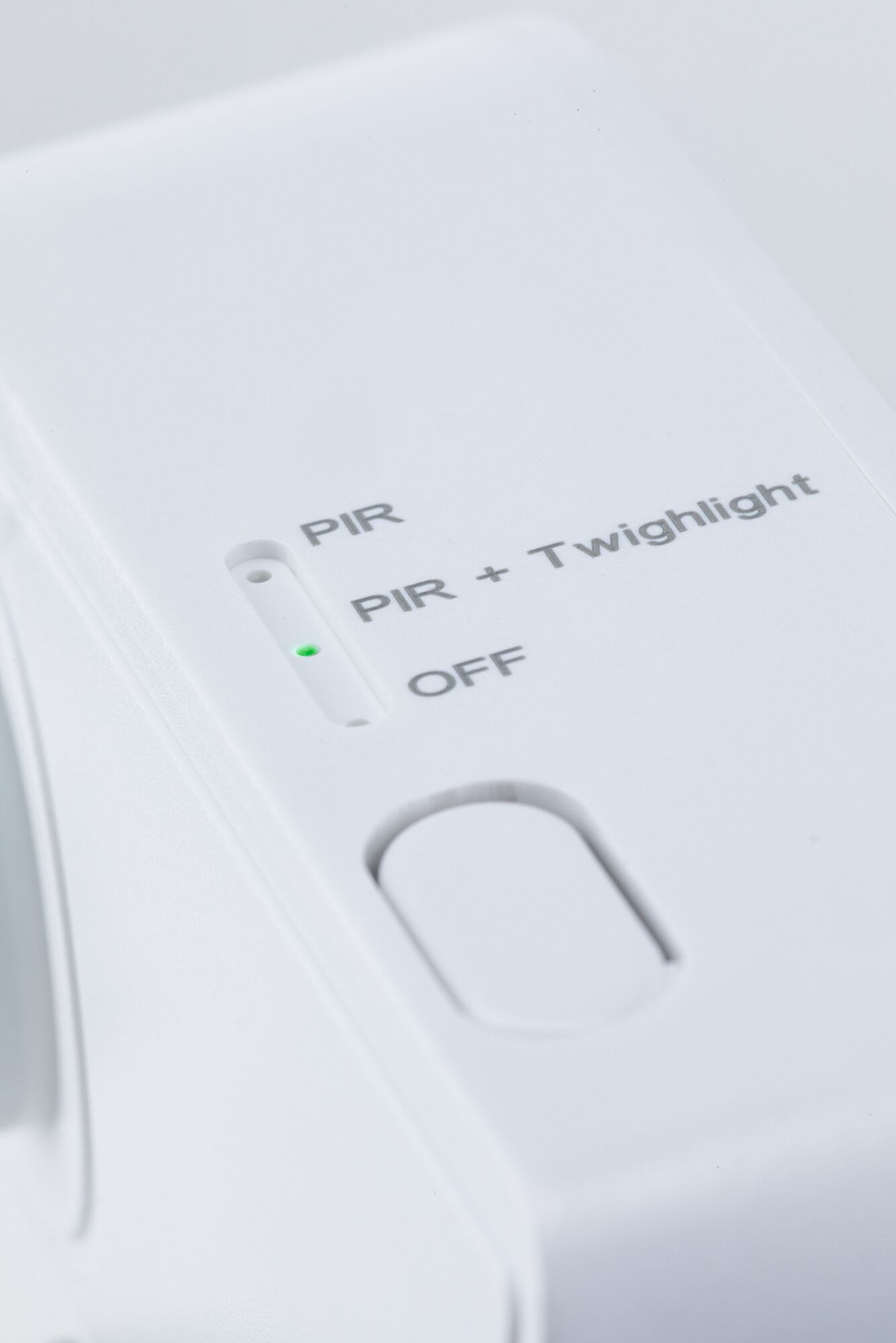 White electronic device with switch for PIR, PIR + Twilight, and Off mode, green LED indicator