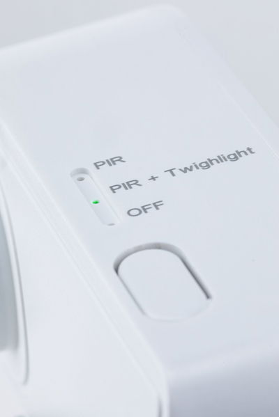 White electronic device with switch for PIR, PIR + Twilight, and Off mode, green LED indicator