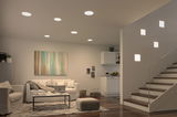 Modern living room with white recessed ceiling lights and square wall lamps on stairs, wooden floor