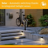 Modern outdoor lighting with integrated twilight sensor illuminating concrete steps and pathway at dusk