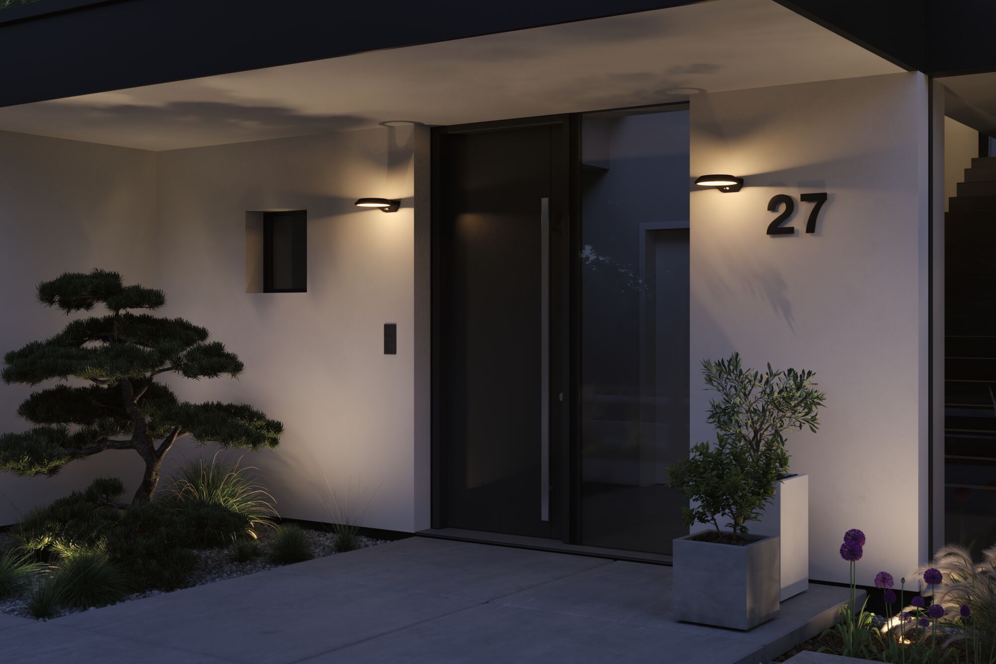 Modern outdoor lighting with black wall lamp on white facade by front door and plants at night.