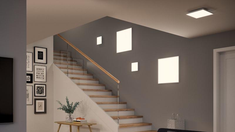 Moderne halverlichting met vierkante warmwitte LED-wandlampen op grijze muur naast houten trap