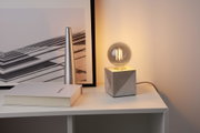 Moderne bordlampe med grå betonfod og rund LED-pære på hvid hylde til boligbelysning