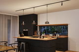 Modern kitchen with black wood finish, wooden countertop, three pendant lights, and bar stools