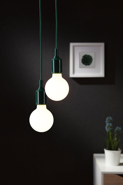 Zwei hängende LED-Glühbirnen mit grünem Kabel vor dunkler Wand, moderne Wohnraumbeleuchtung.