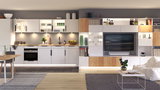 Cuisine blanche moderne avec plan de travail en bois et éclairage LED intégré dans un salon ouvert avec TV.