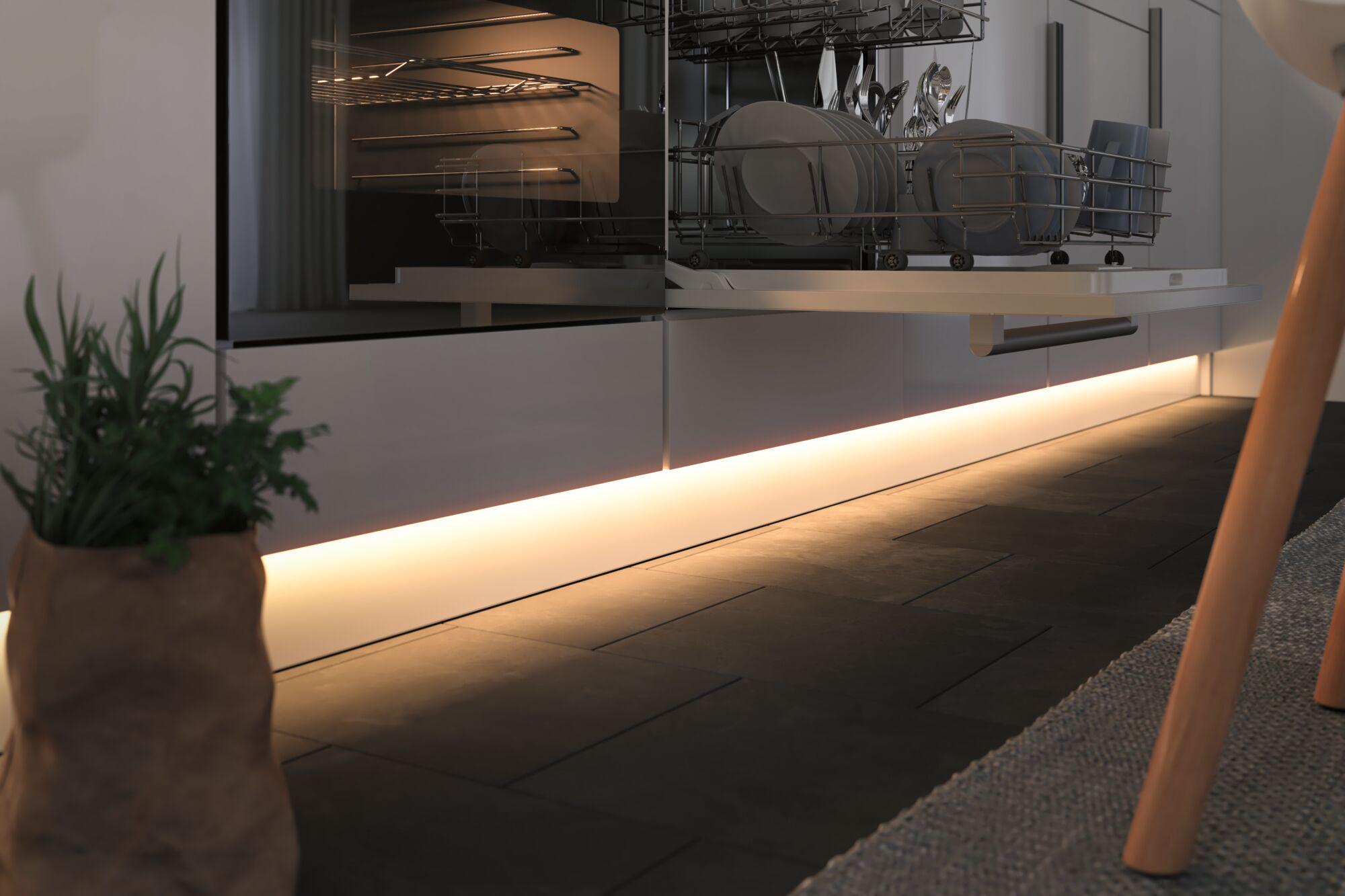 Modern kitchen with open dishwasher and warm white LED floor lighting creating cozy ambiance