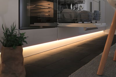 Cuisine moderne avec lave-vaisselle ouvert et éclairage LED blanc chaud au sol pour une ambiance chaleureuse