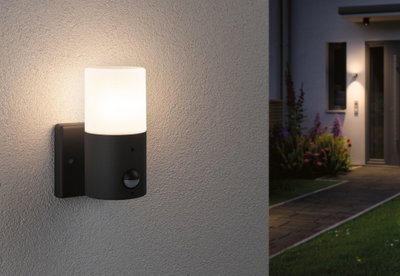 Moderne Außenwandleuchte aus schwarzem Metall mit weißem Glas und Bewegungsmelder für Gartenbeleuchtung.