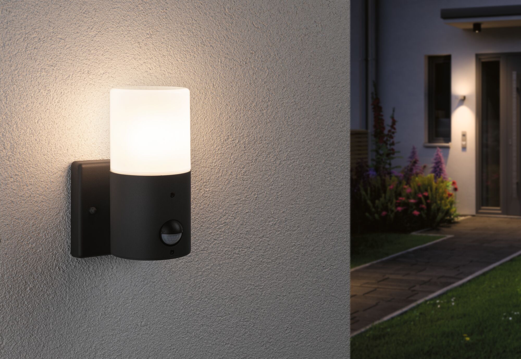 Moderne schwarze Außenwandleuchte mit weißem Glas und Bewegungsmelder an Hauswand bei Nacht