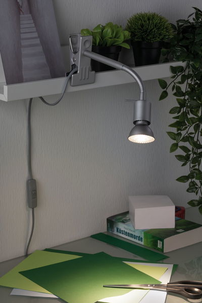 Grå LED-klemme spotlight med fleksibel arm på hylde, lyser på grønt hobby papir på skrivebord med saks.