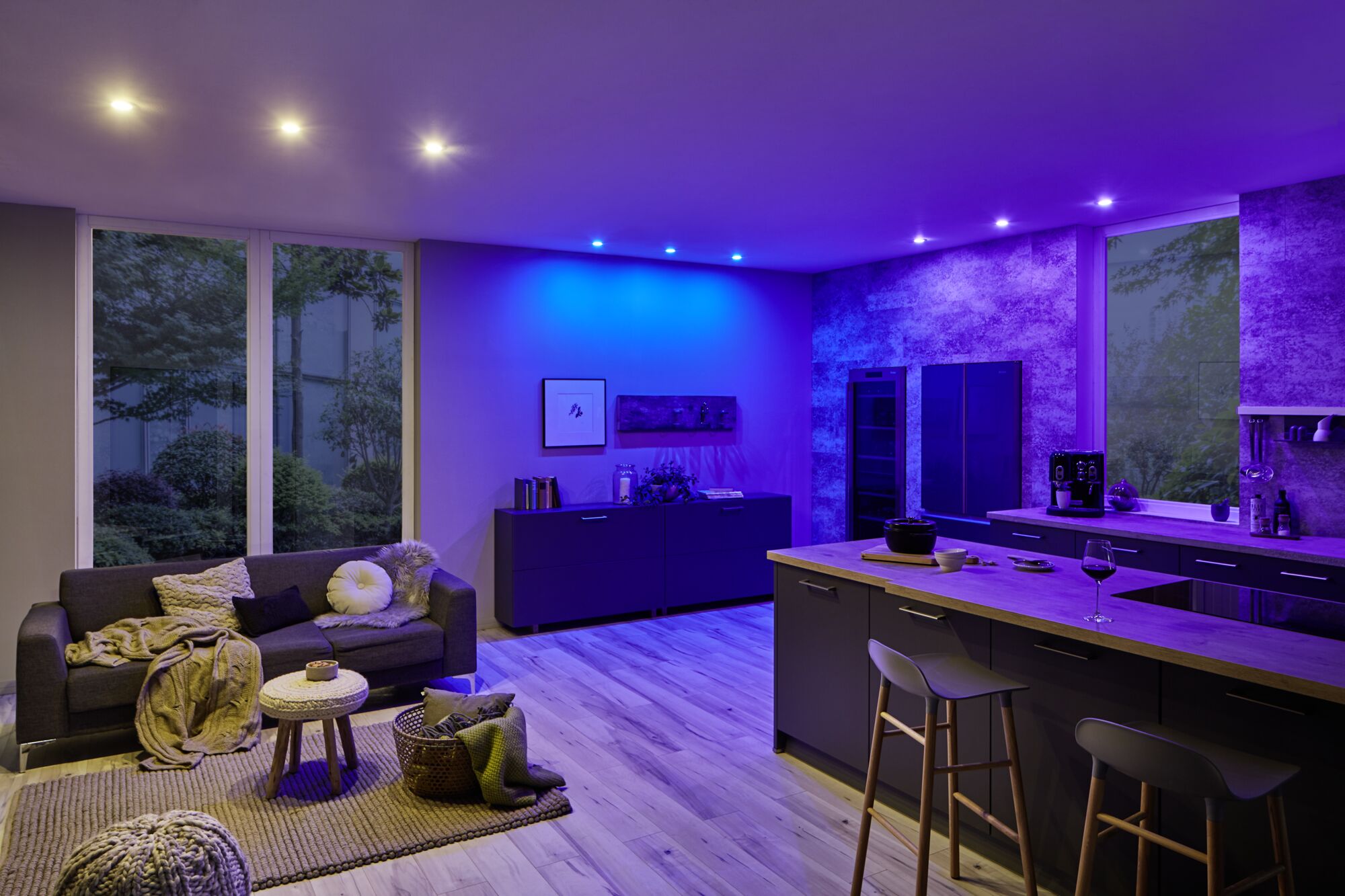 Salon moderne avec éclairage LED bleu au plafond et cuisine ouverte avec plan de travail en bois
