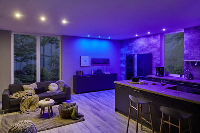 Salon moderne avec éclairage LED bleu au plafond et cuisine ouverte avec plan de travail en bois
