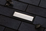 Rechthoekige zwarte LED-inbouwlamp met wit licht op donkere bestrating voor buitengebruik